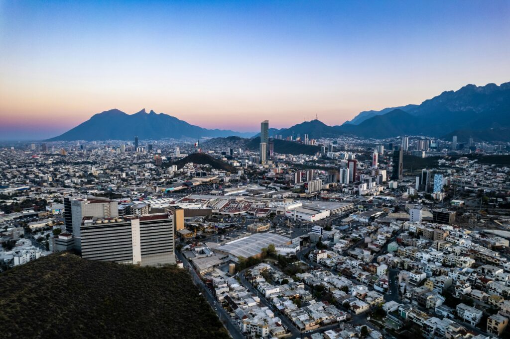 Hoteles cerca del Estadio BBVA para el Mundial 2026: dónde hospedarse en Monterrey Capture of Monterrey's skyline with high-rise buildings and mountains at dusk.