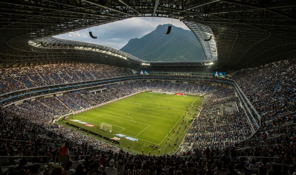 A vibrant football match at Estadio BBVA with a backdrop of Cerro de la Silla, Monterrey.