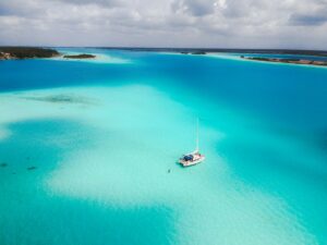 A stunning aerial view of a sailboat in the tranquil turquoise waters of Bacalar Lagoon, Mexico.